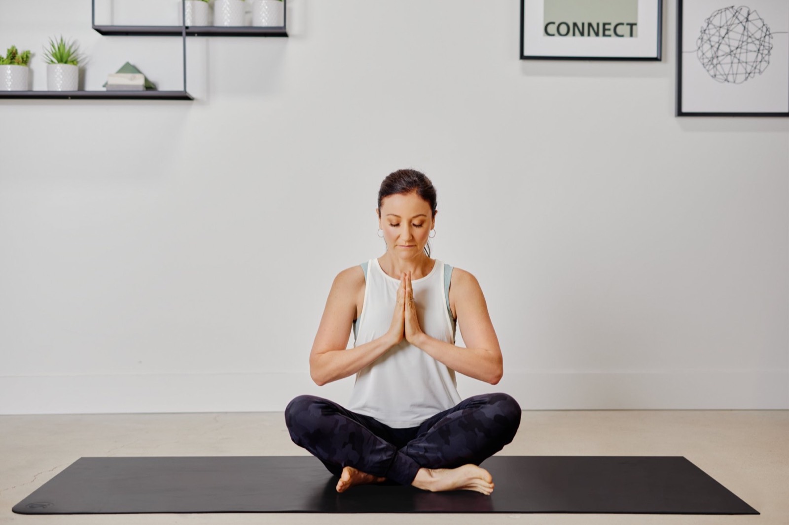 April meditating cross-legged on a yoga mat